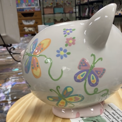 Decorative piggy bank with colorful butterfly designs on a wooden surface.