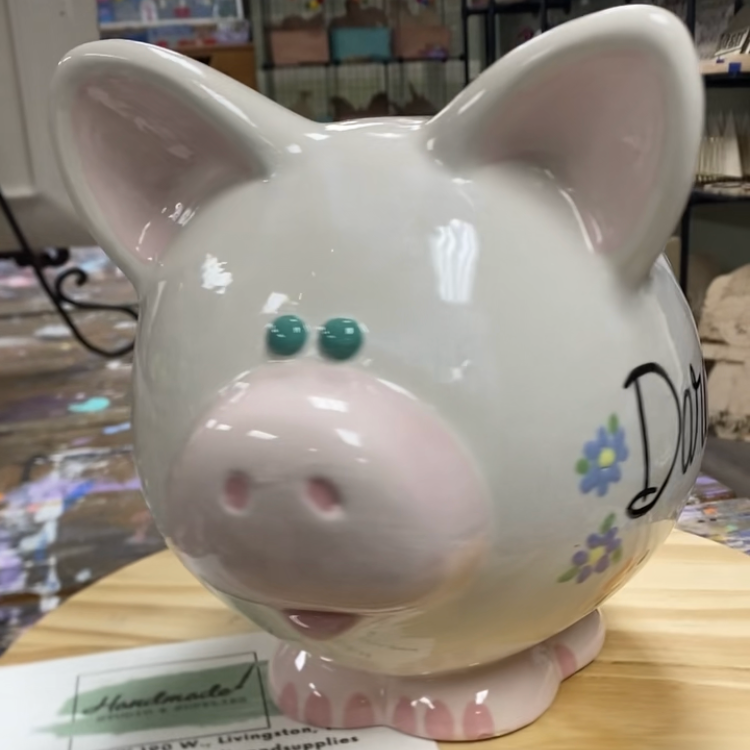 White piggy bank with floral designs on a wooden surface
