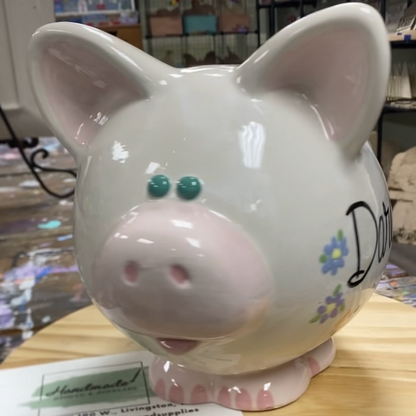 White piggy bank with floral designs on a wooden surface