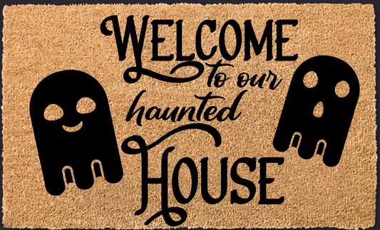 Doormat with 'Welcome to our haunted house' text and skull designs on a black background