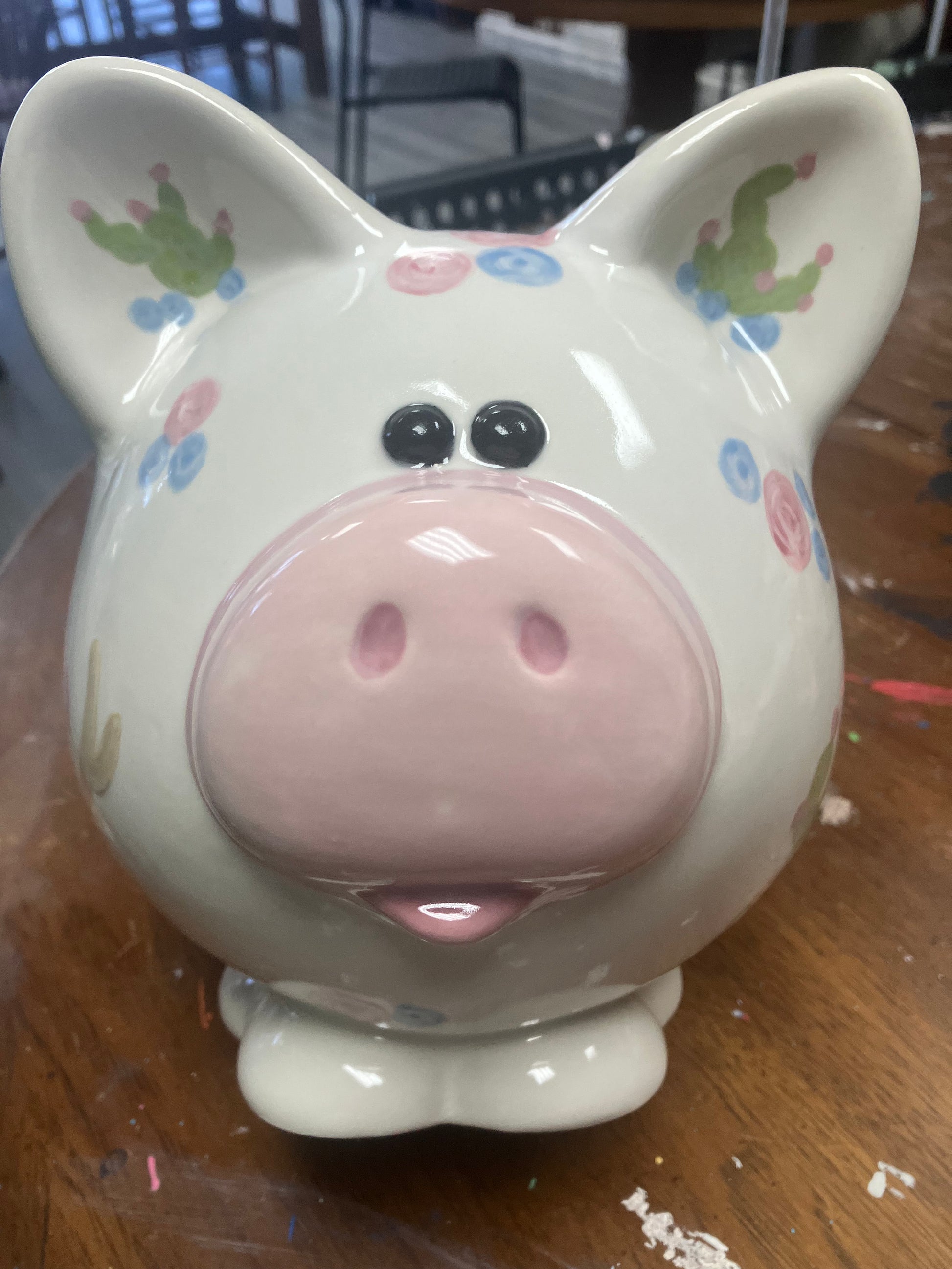 Decorative pig-shaped container with floral patterns on a wooden surface