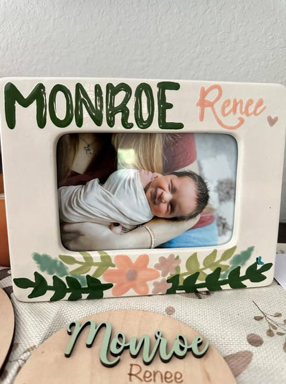 Decorative picture frame with floral design and text 'Monroe Renee' on a plain background