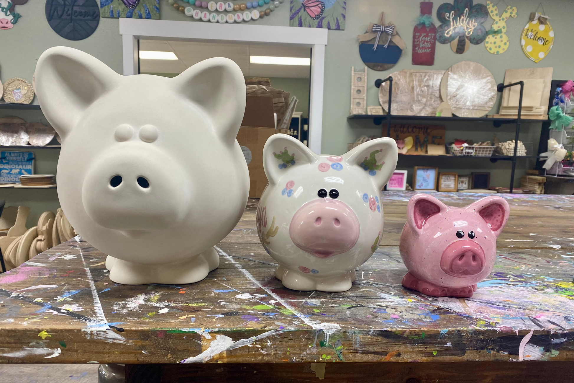 Three piggy banks of different sizes on a table with a classroom setting in the background.